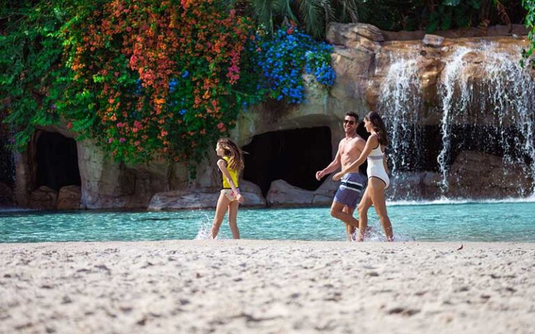 family walking along beach area with waterfalls at discovery cove orlando