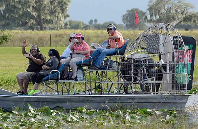 fanboat with tourists rides through wetlands at kissimmee swamp tours florida