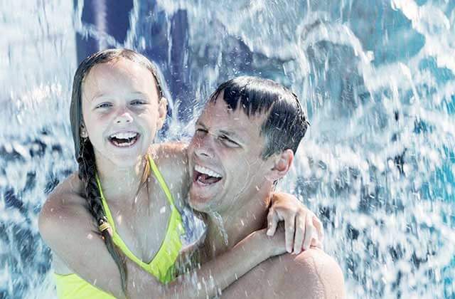 father and daughter laughing while splashing in water at adventure landing shipwreck island waterpark