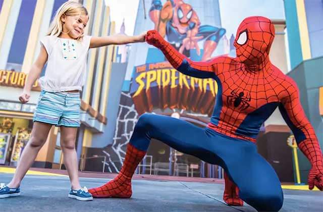 girl bumps fist with costumed spiderman character in front of ride at universals islands of adventure theme park orlando