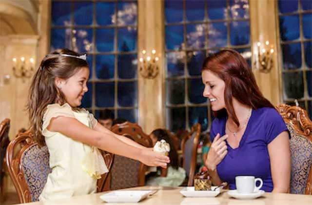 girl giving cupcake to mom in a formal dining room at disney magic kingdom theme park orlando