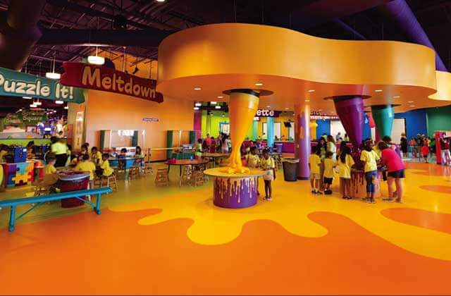 kids gather around orange craft kiosks under meltdown sign at crayola experience orlando