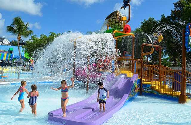 kids play under a pouring water feature with slides at rapids water park west palm beach