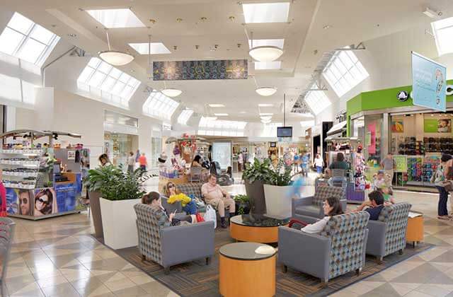 People enjoy lounging in chairs in corridor of indoor shopping mall