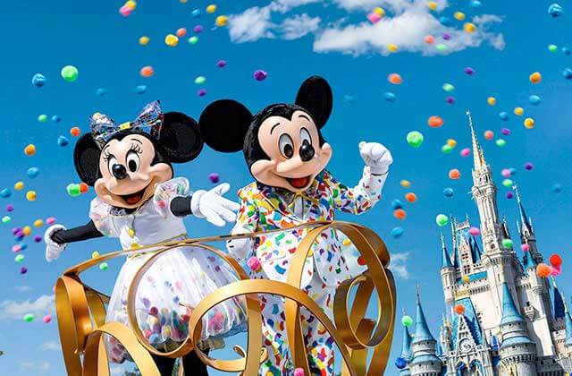 mickey and minnie in formal dress on a parade float with cinderella castle in the background at disney magic kingdom theme park orlando