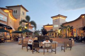 outdoor mall with shoppers at tables and benches at coconut point estero florida