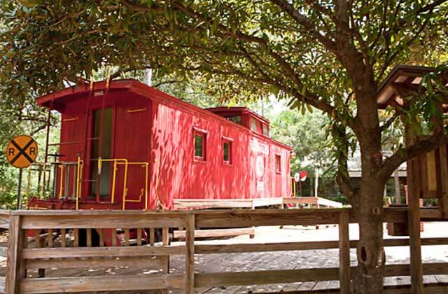 red caboose train car exhibit under the trees at tallahassee museum florida