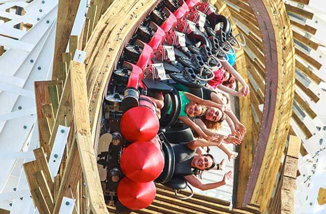 riders with arms in the air on a red roller coaster with wooden rails sideways at fun spot america kissimmee