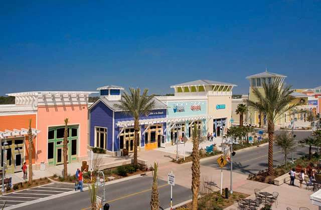 row of colorful storefronts near beach with sidewalks at pier park panama city beach