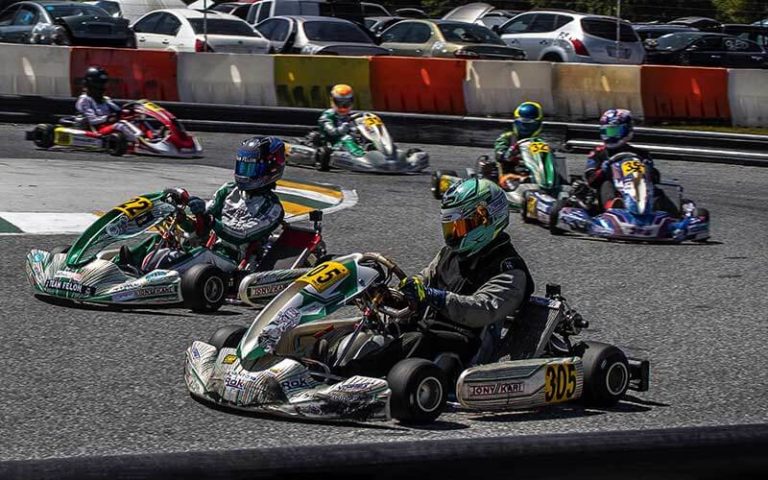 several kart racers in helmets racing around bend on track at orlando kart center