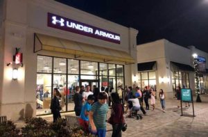 shoppers outside an under armour storefront at night at palm beach outlets west palm beach