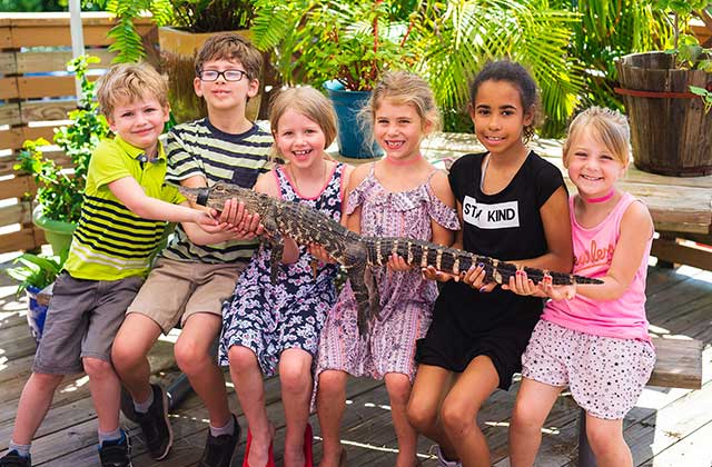 six kids smiling holding young alligator with taped mouth at everglades holiday park