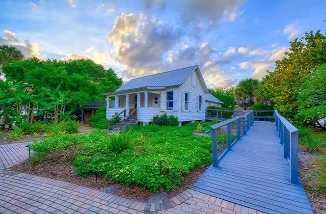 small historic home with blue ramp bricked walkway and lush landscaping at jupiter inlet lighthouse museum florida