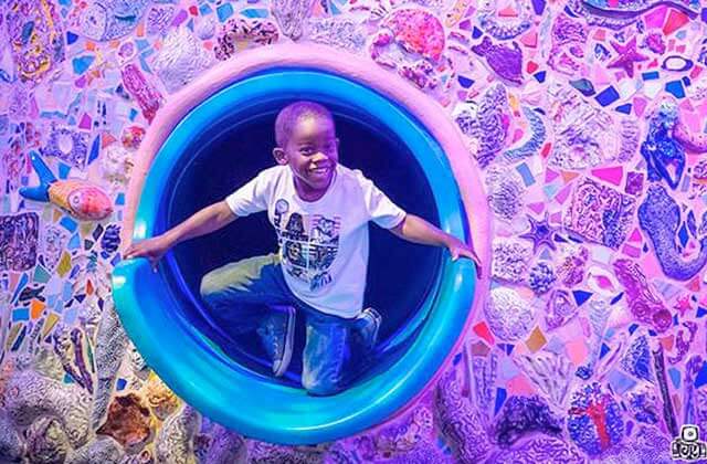 smiling boy emerges from slide tube at miami childrens museum florida