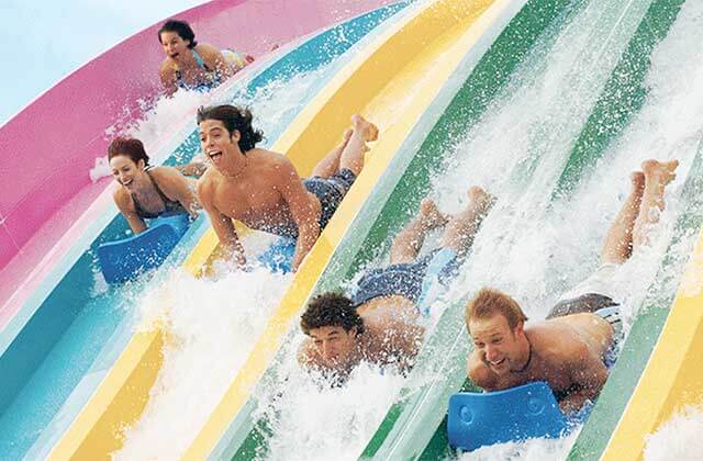 teens race on mats down multi colored water slides at aquatica water park orlando