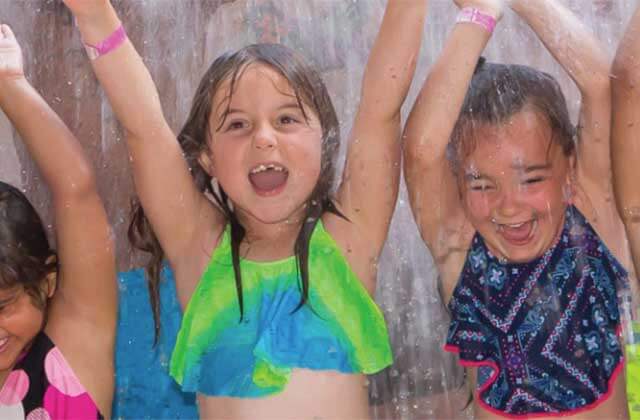 three girls with arms raised screaming and getting soaked at big kahunas water adventure park destin