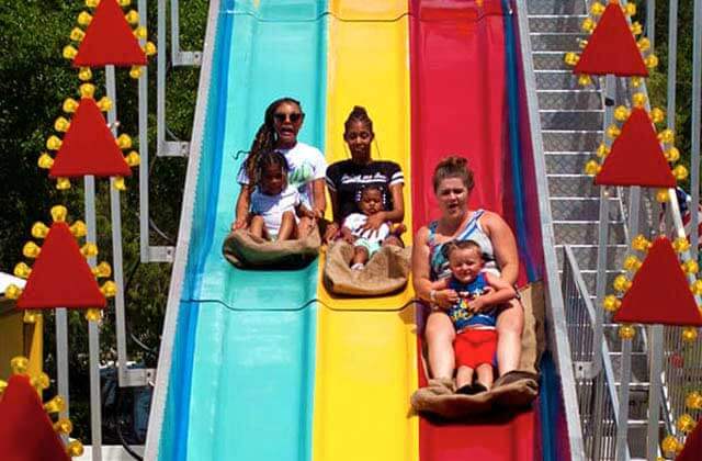 three moms with toddlers in their laps slide down multi colored slides at fun spot america kissimmee