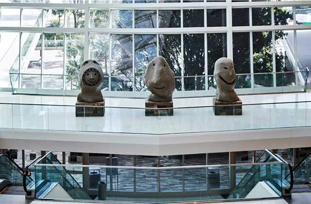 three stone statues in the atrium over staircase at aventura mall florida