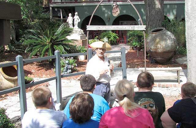 tour guide in period costume teaches group in garden area at oldest wooden school house st augustine