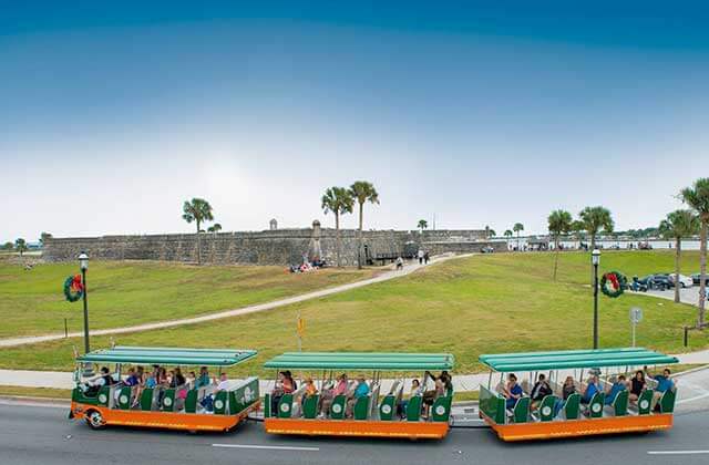 trolley bus passing a fort on a hill at old town trolley tours st augustine