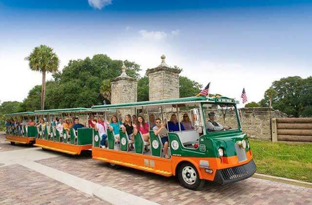 trolley bus with passengers waving along cobble stone street at old town trolley tours st augustine