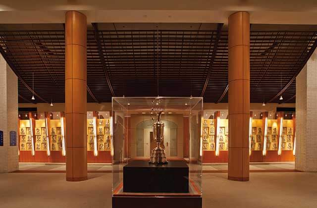 a trophy in a display case with gold statues of golfers along wall at world golf hall of fame museum st augustine
