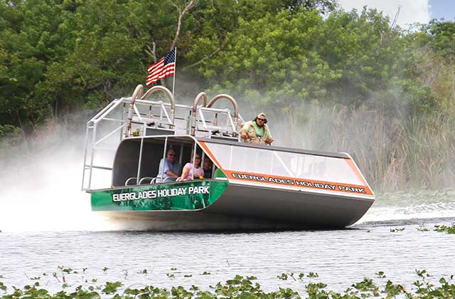 twin engine large covered airboat speeding across marsh with large group of riders at everglades holiday park