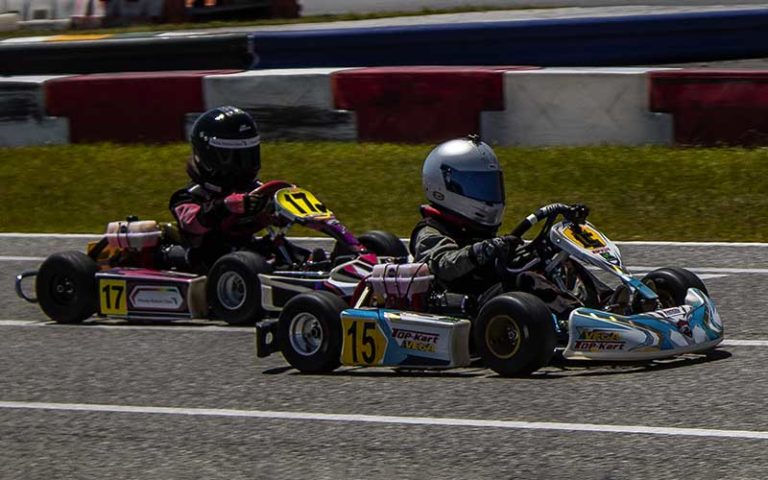 two kart racers with helmets and stickers speeding across track at orlando kart center