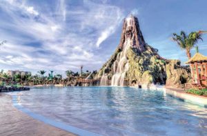 view of beach area with volcano and cascading waterfall at universals volcano bay water park orlando