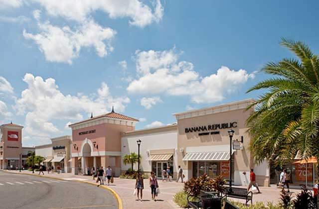 view of parking lot at shopping center with storefronts and palm tree at orlando international premium outlets florida
