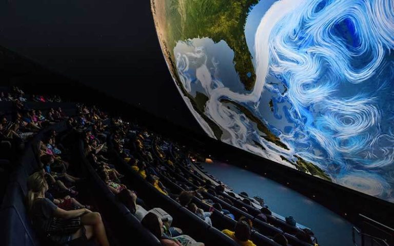 viewers seated in a spherical theater with earth on screen at frost science miami florida