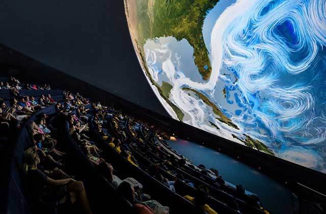 viewers seated in spherical theater with earth on screen at frost science miami florida