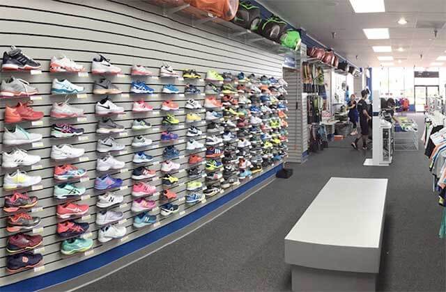 wall of selection of sport shoes with fitting bench at tennis plaza florida stores