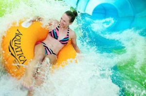 woman laughing and riding yellow tube on water slide ride at aquatica orlando