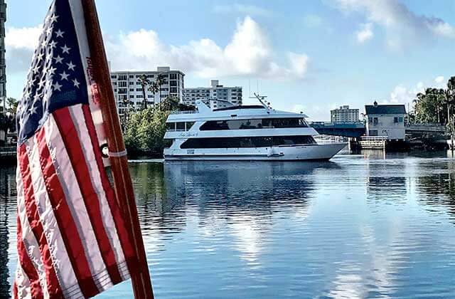 yacht moving through inlet with us flag at delray yacht cruises