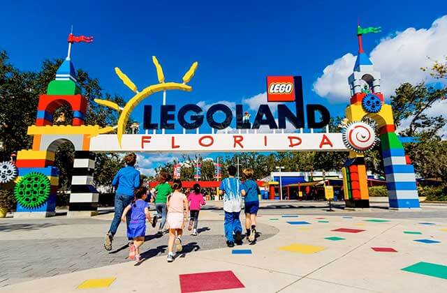 group of kids running toward the front entrance gateway with sign at legoland florida resort