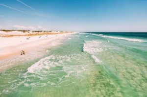 lapping green blue waves on a gulf beach with families jetty dunes and blue umbrellas for panama city destination feature