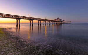 sunset reflecting on surf at beach with pier lights fort myers feature