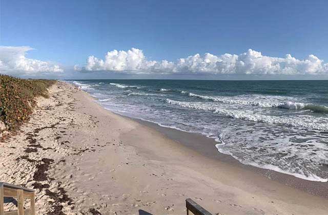 view from boardwalk down a deserted beach at playalinda beach canaveral national seashore