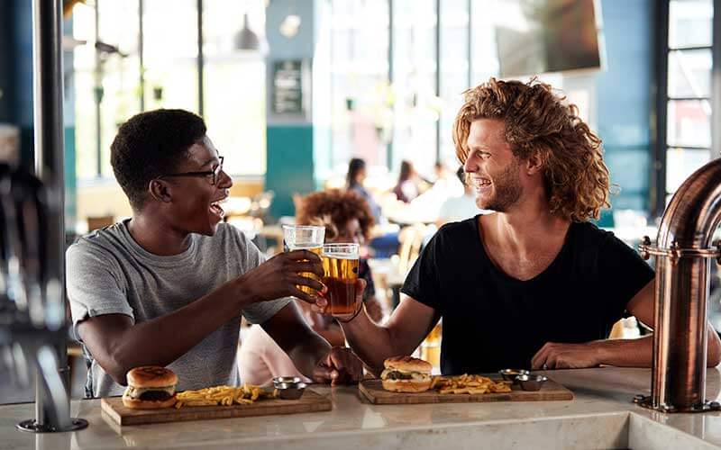 two male friends eating food and drinking beer from happy hour in central florida post