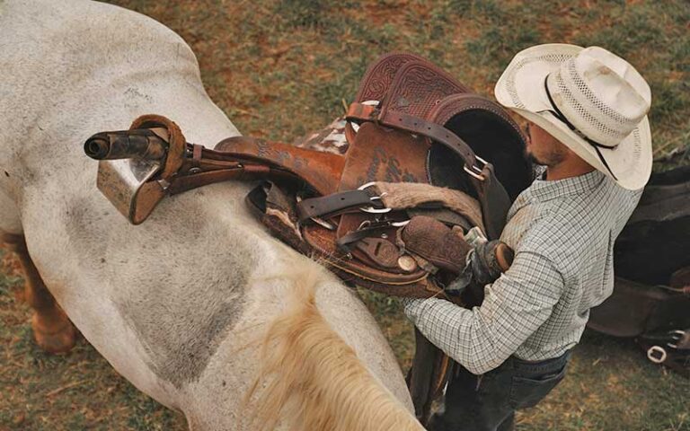 aerial of cowboy putting saddle on horse at boot barn orlando kissimmee