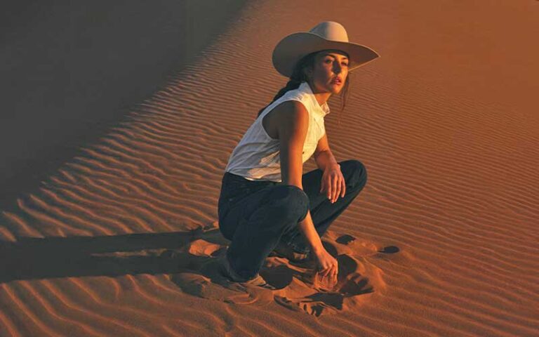 cowgirl kneeling in desert sand at boot barn orlando kissimmee