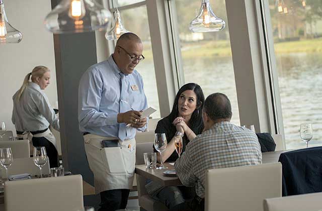 interior view of paddlefish restaurant with server and couple at table placing order at disney springs lake buena vista orlando