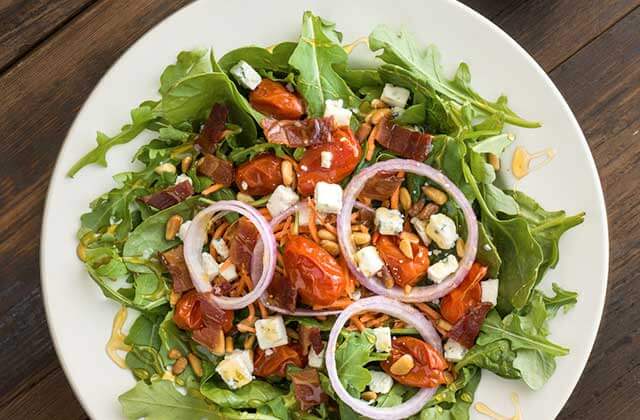 large salad in serving bowl topped with blue cheese cubes red onion and sun dried tomatoes at flippers pizzeria orlando kissimmee