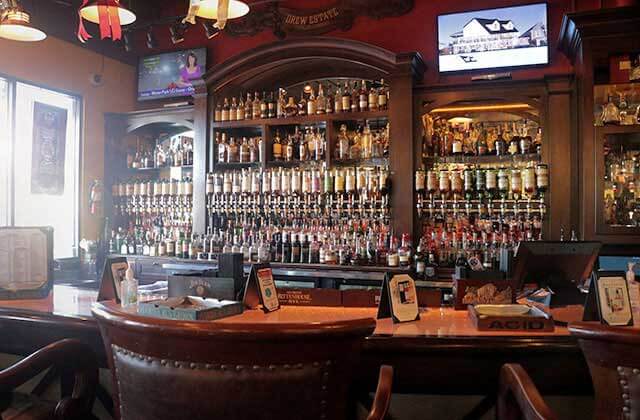 liquor bar with wall of bottles wood interior and leather chairs at corona cigar company orlando