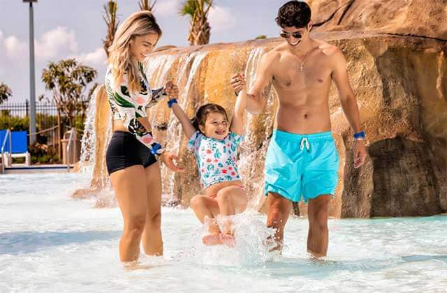 man and woman with toddler wading through splash zone at island h2o live waterpark kissimmee