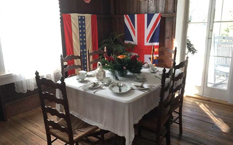 set dining table in old dining room with colonial flags at pioneer village
