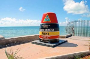 southernmost point marker with blue ocean and a few clouds on the skyline for key west destination feature