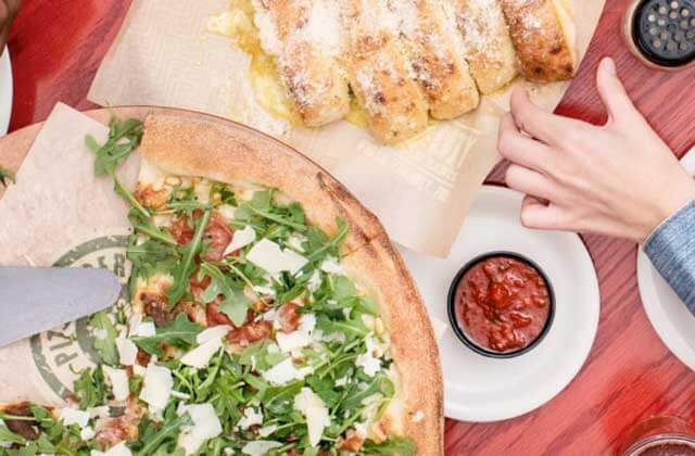 tabletop with a healthy pizza breadsticks and sauce at flippers pizzeria orlando kissimmee