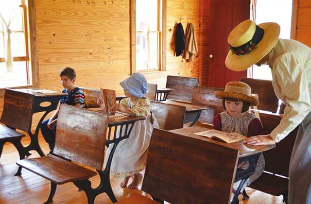 teacher and kids in period costume in historic schoolhouse at pioneer village shingle creek kissimmee